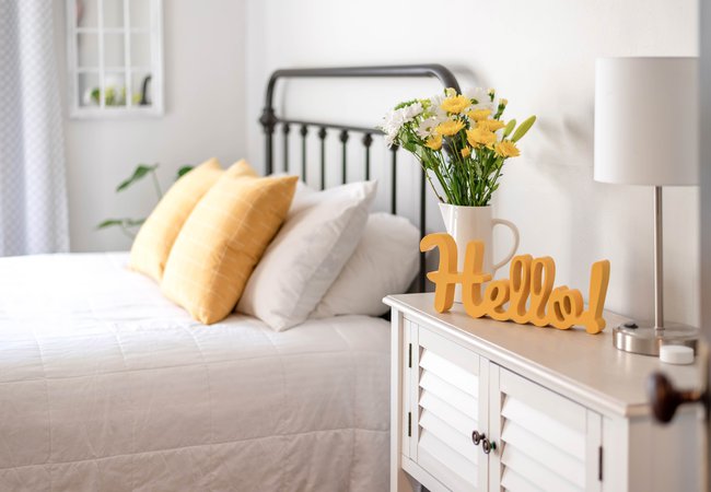 Cheerful-hello-sign-in-clean-and-bright-bedroom-with-yellow-accents
